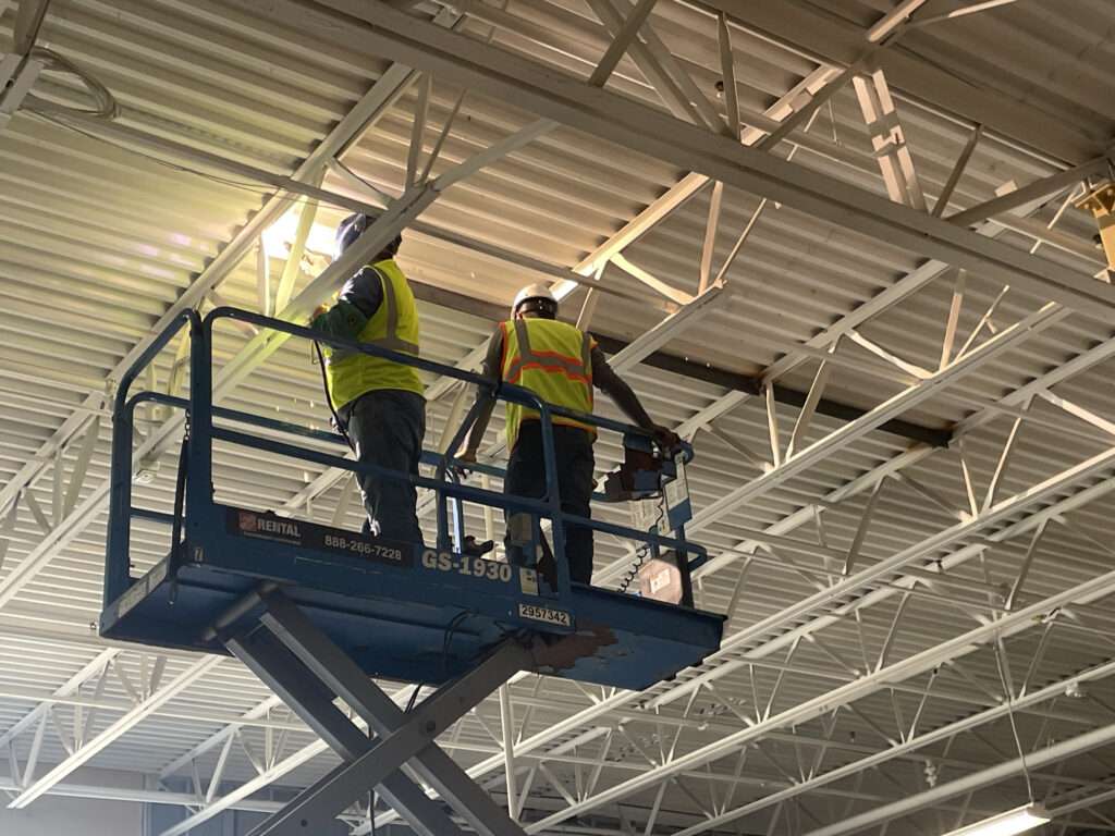 AWS certified mobile welder installing structural steel RTU supports on a commercial rooftop in Houston.