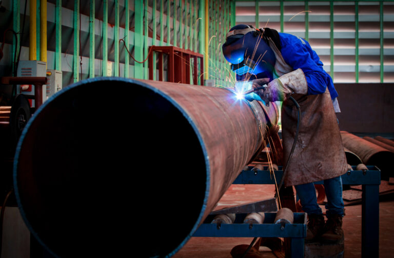 Technician welding pipes on-site for a custom pipe fabrication project