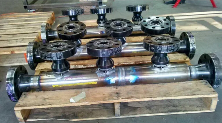 Batch of custom fabricated carbon steel pipe manifolds with flanged branch connections on a pallet.