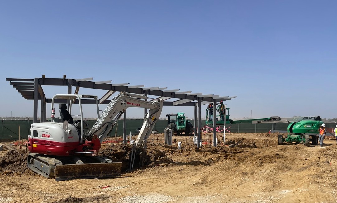 Ironworkers performing structural steel erection on a commercial building site in Houston, utilizing a crane to position heavy I-beams.